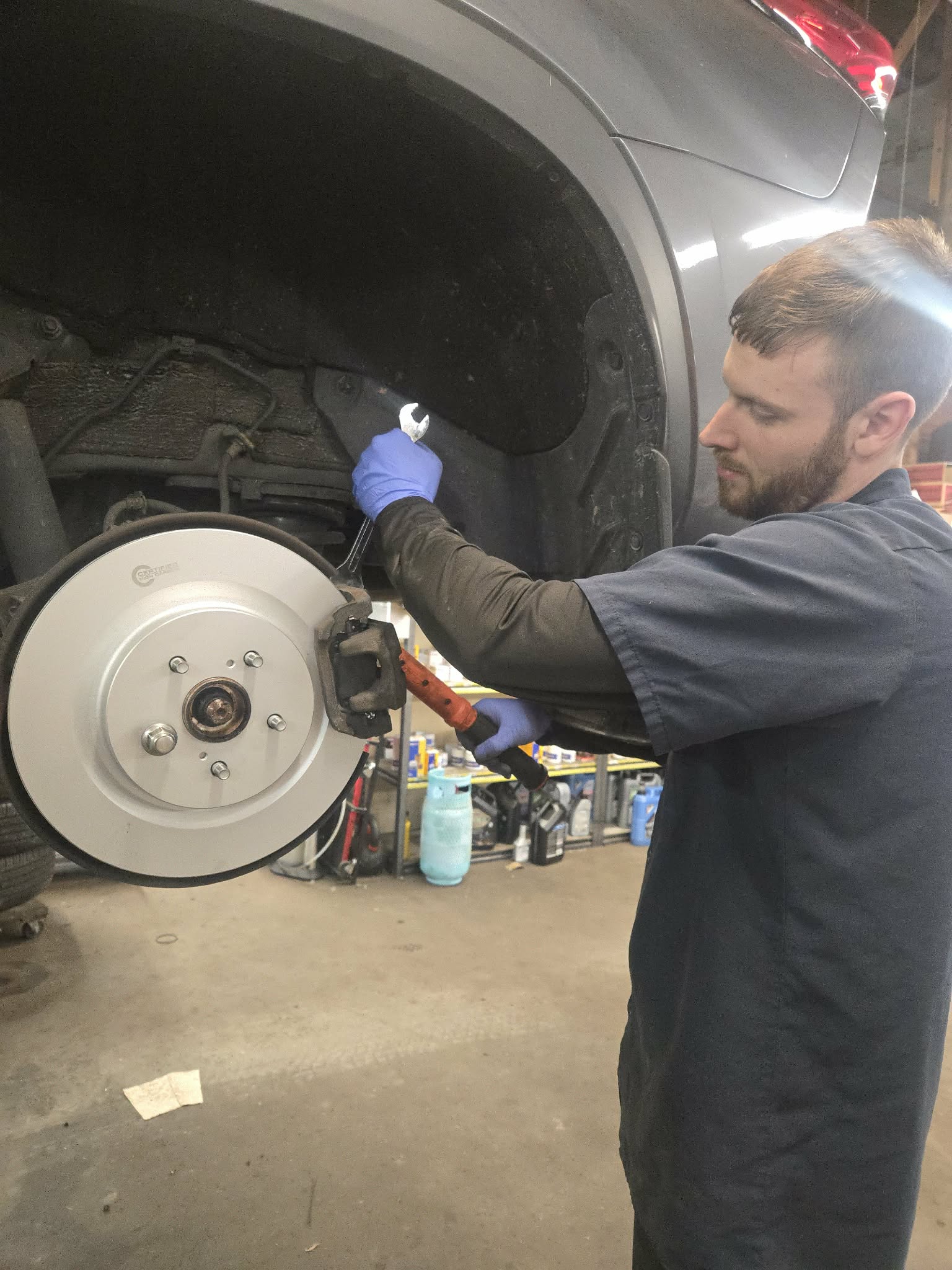 Bobby removing a brake caliper during a brake pad replacement at POCO NAPA AUTOPRO